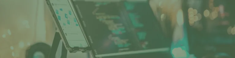 A smartphone displaying a Melbourne web design website stands on a desk next to a computer screen with lines of code, reminiscent of a café serving up creativity and smashed avo delights.