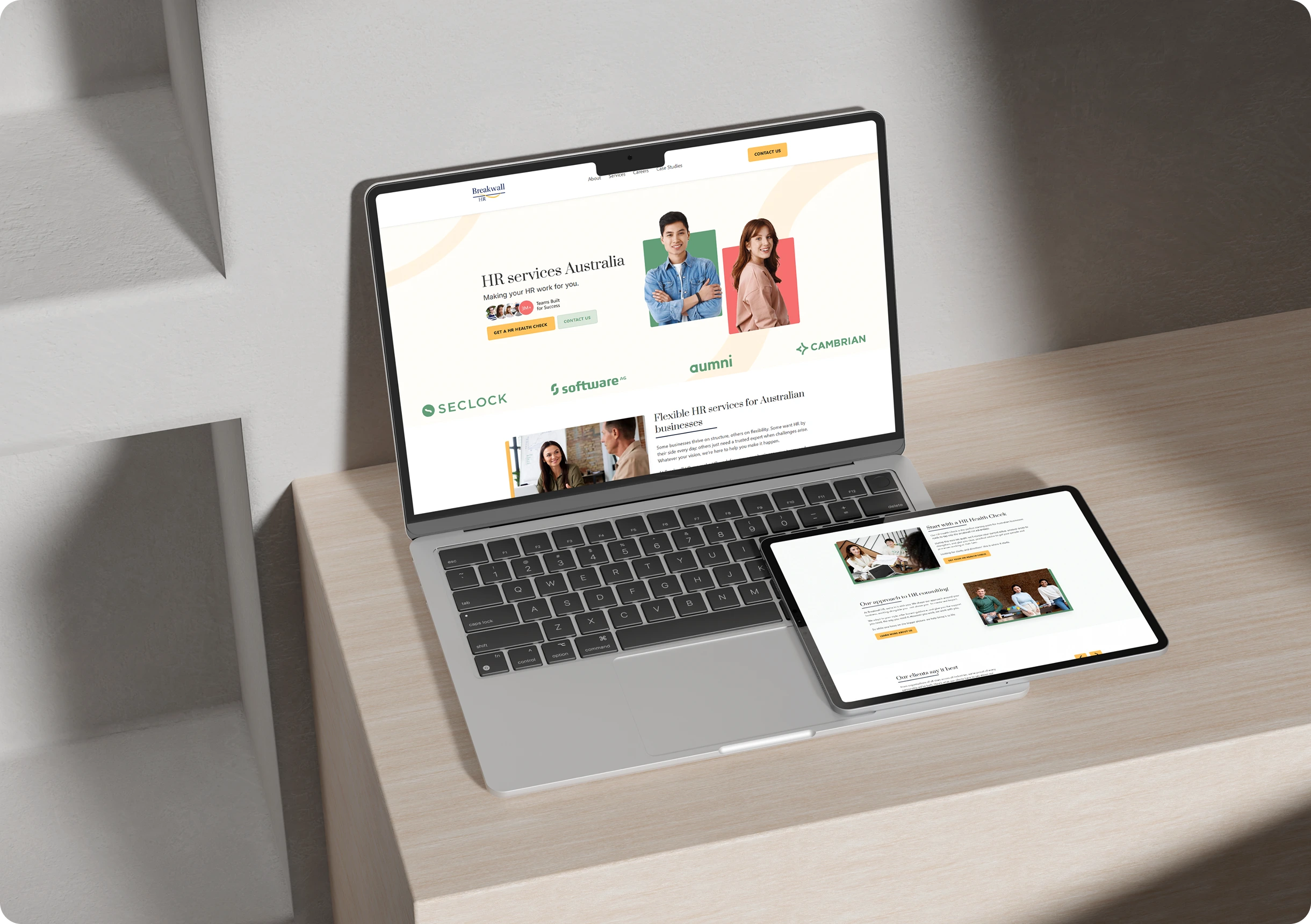 A laptop and a tablet on a desk display the same HR services Australia website, featuring logos and images of people on the screens.