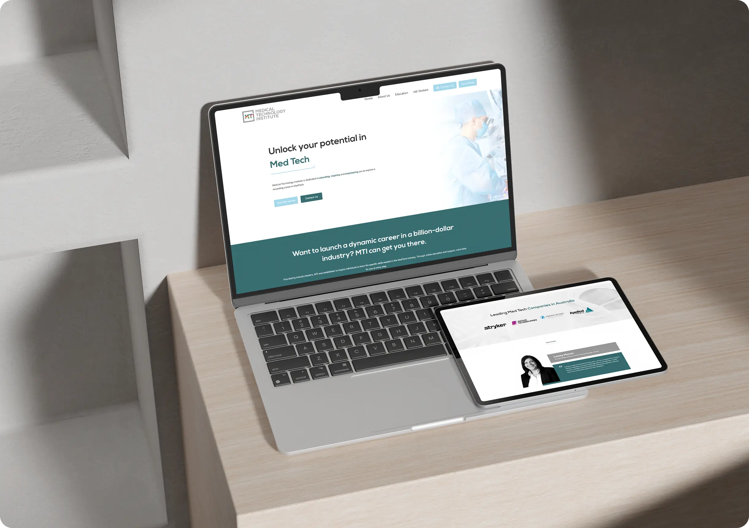 A laptop and a tablet on a light wood desk display the same website for a Med Tech career program.
