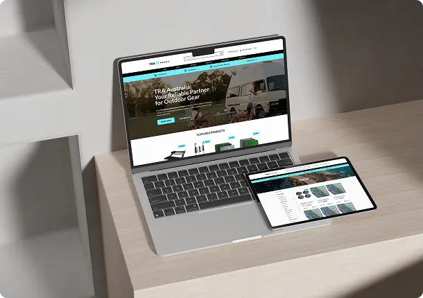 A laptop and a tablet on a light wood desk display the homepage of an outdoor gear website, featuring camping products and equipment.